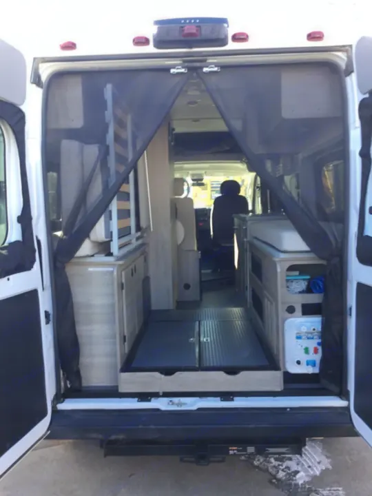 This RV rental shows a camper van interior with a rear screen, modular bed, and custom storage cabinets.. Winnebago Solis 2021