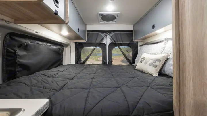 Step inside this RV rental! A comfortable bed awaits, offering stunning mountain and lake views from the rear camper doors.. Winnebago Solis 2021