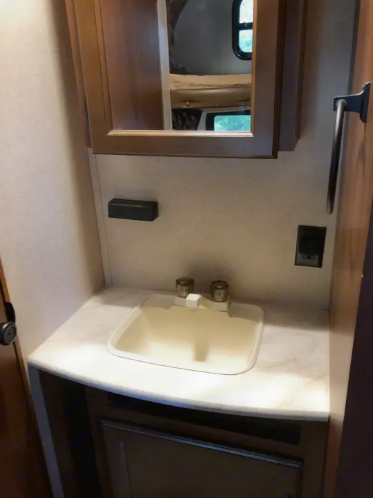 RV rental bathroom with a compact sink, mirror reflecting bunk beds, toilet paper holder, and outlet.. Jayco Jay Flight 2015