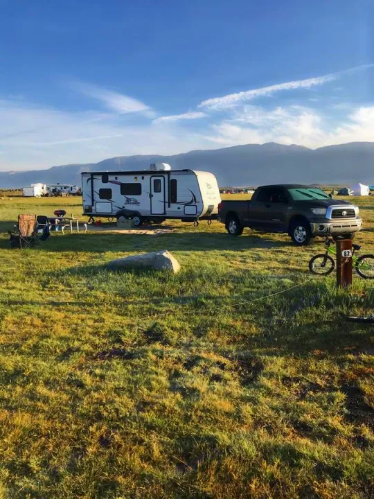 Spacious campsite with RV rental, pickup truck, chairs, and bike. Mountains and other campers in background.. Jayco Jay Flight 2015