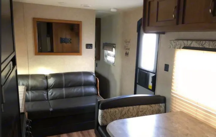 Inside an RV rental: a cozy living area with a black sofa, dinette, and functional layout for your adventures.. Coachmen Catalina 261 2019