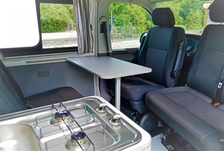 RV rental: Camper van interior with two-burner stove, adjustable table, & swiveling front seats.. Volkswagen Transporter T6.1 2021
