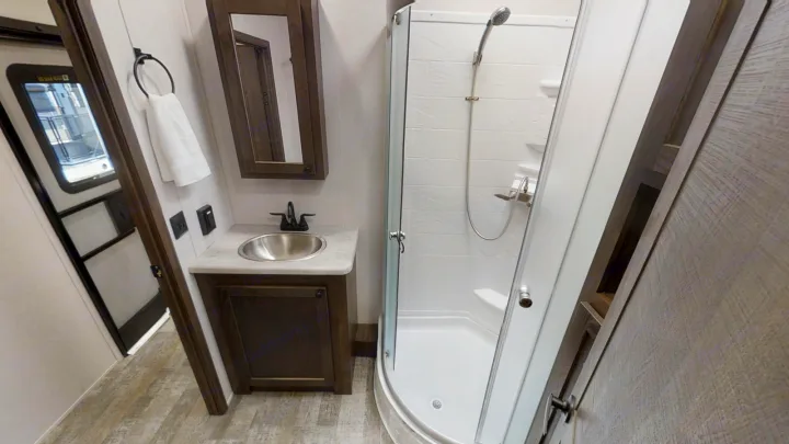 Explore the compact yet functional bathroom in this RV rental, complete with a sink, mirror, and shower.. Forest River XLR HYPERLITE 2815 2021