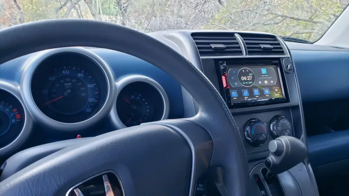 Dashboard view in an RV rental, featuring steering wheel, instrument cluster, and a touchscreen head unit showing 04:27.. Honda Element 2003