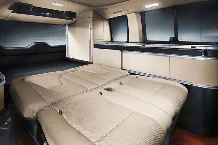 Interior of a cozy RV rental, showing a bed setup from folded seats & storage cabinets. Ideal for camper van travel.. Mercedes Marco Polo Class V 250d 2022