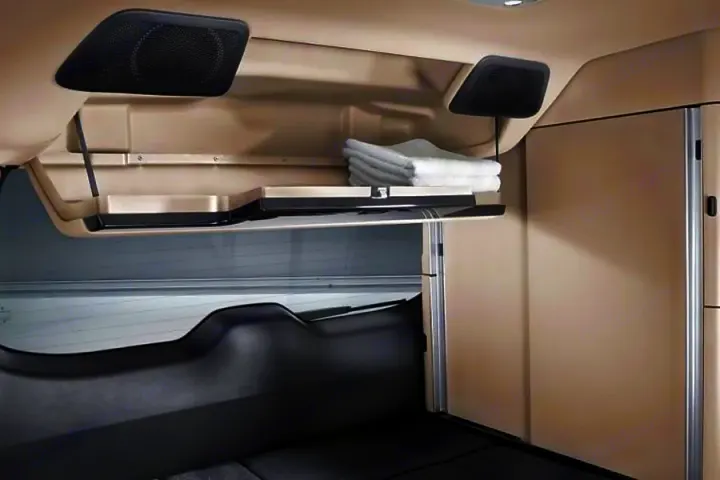RV rental overhead storage is open, showing folded towels. Speakers and a sleeping area are visible in this clean cabin interior.. Mercedes Marco Polo Class V 250d 2022