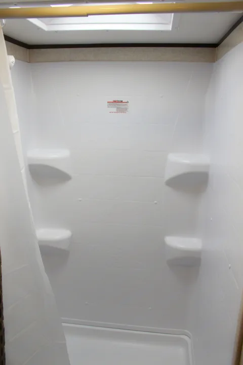 Inside a clean, compact RV rental shower with built-in shelving & overhead skylight.. Jayco Jay Flight SLX Rocky Mtn Edition 2019