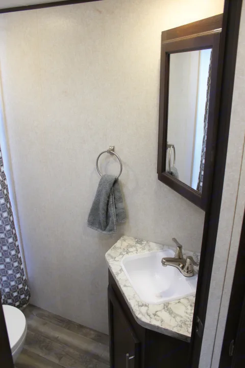 Clean, compact RV rental bathroom with sink, faucet, mirror, and towel. Ideal for road trips.. Jayco Jay Flight SLX Rocky Mtn Edition 2019