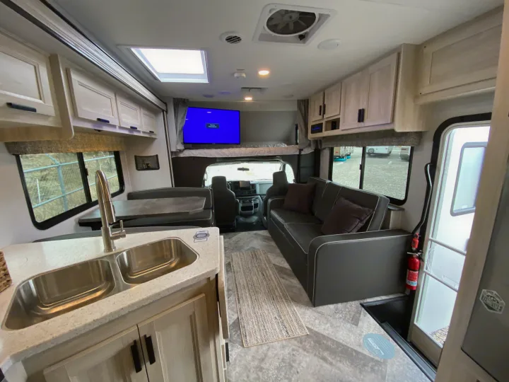 Modern rv rental interior: kitchen, dinette, sofa, and overhead bunk. Bright and inviting for your next journey.. Forest River Forester 2021