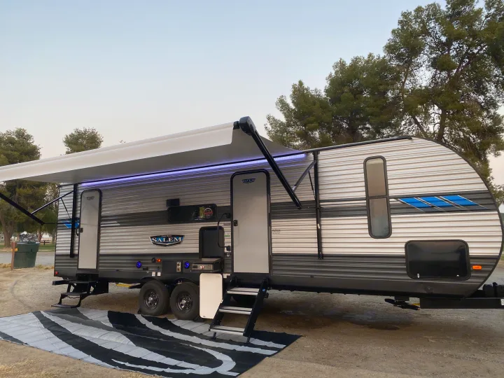 An RV rental parked on a gravel campsite.. Forest River Salem 2021