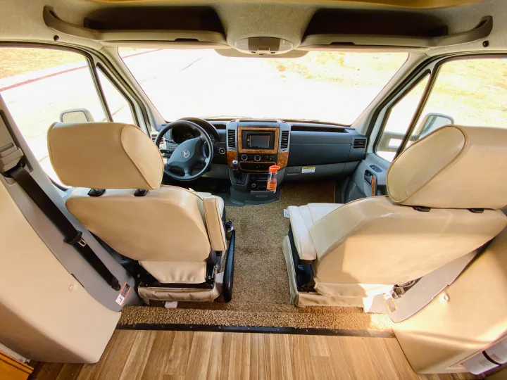 Spacious RV rental interior featuring comfortable captain's chairs and a well-equipped dashboard, ready for your journey.. Thor Motor Coach Other 2016