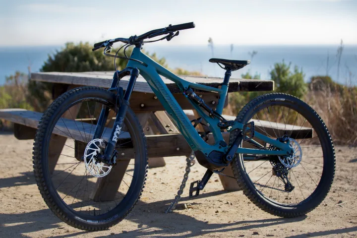 A teal Specialized e-mountain bike is parked by a picnic table, with an ocean view in the background. Perfect for RV rental adventures.. Other Other 2021