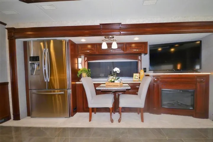Luxury RV rental interior: a spacious living area with a full kitchen, dining table, fireplace, and large screen TV for comfort.. Entegra Coach Anthem 44B 2017