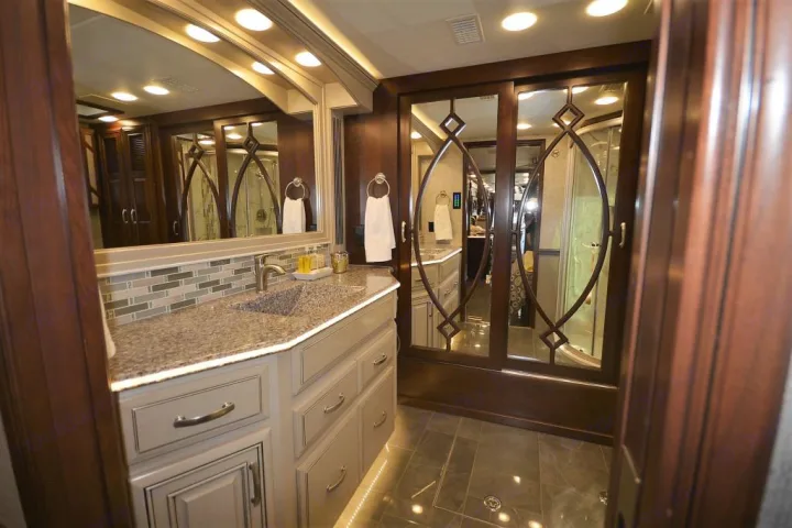 Modern RV rental bathroom with a spacious vanity, under-cabinet lighting, and mirrored shower doors.. Entegra Coach Anthem 44B 2017