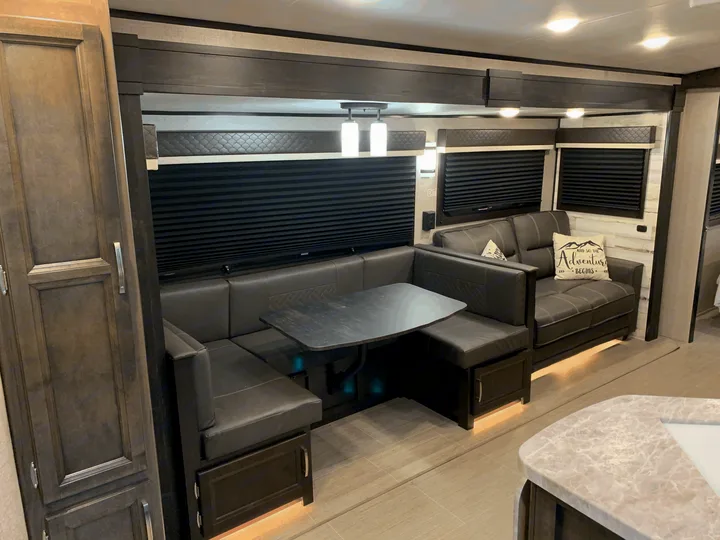 Modern RV rental interior with a dark gray dinette, comfortable sofa, and sleek design. Ready for your adventure.. Jayco White Hawk 2021