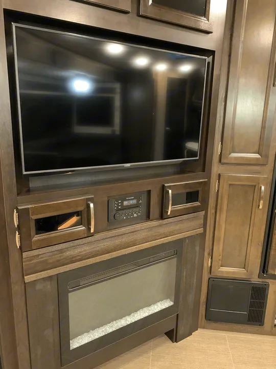 This cozy rv rental entertainment center features a Vizio TV, IRV Technologies stereo, electric fireplace, and storage cabinets.. Jayco White Hawk 2021