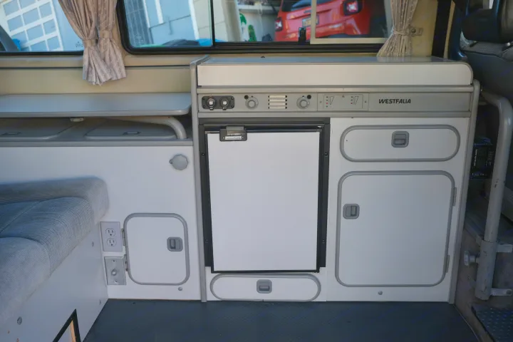 RV rental: Westfalia camper interior with kitchen, fridge, storage, bench seating, and power outlets.. Volkswagen Westfalia 1990