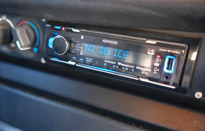 Close-up of a Kenwood car stereo displaying "NO DEVICE" on an RV rental dashboard, with USB port and climate controls visible.. Volkswagen Westfalia 1990