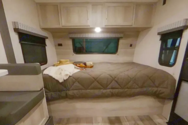 Cozy RV rental bedroom with a large bed, windows, and cabinets. Perfect for travel adventures.. K-Z Manufacturing Escape 191bhk 2021