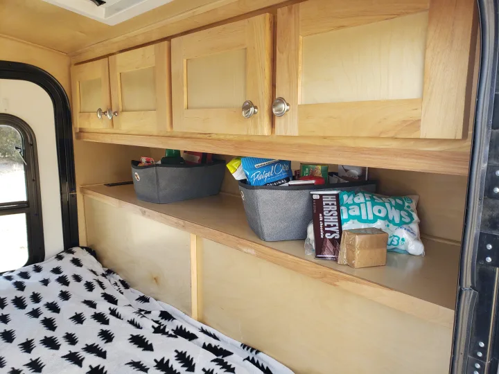Cozy RV rental interior: wooden cabinets & shelves with snacks (Hershey's, marshmallows) for camping.. Escapade Ridge 2018