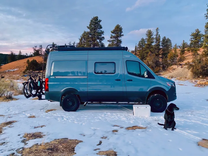 Explore winter with this grey RV rental, bikes, & dog in the snow. An adventure-ready camper van for outdoor travel.. Winnebago Revel 2021