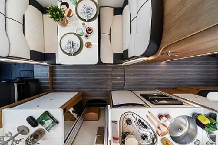 Explore this modern RV rental interior! Features a bright dining area, well-equipped kitchen, and comfortable sleeping/seating.. Ford Rollerteam 747 2026