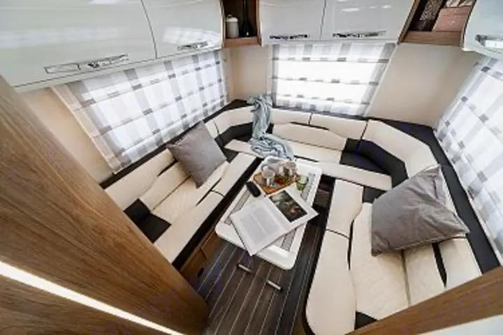 This modern RV rental interior offers a spacious U-shaped lounge, dining table, and large windows. Perfect for cozy travel.. Ford Rollerteam 747 2026