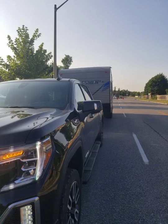 Black GMC truck with an RV rental travel trailer, parked roadside for a trip.. Other Sportsmen 2019