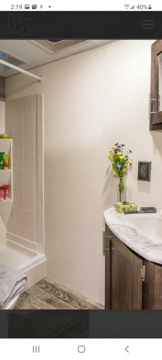 Compact RV rental bathroom with shower, modern vanity, and wood-look flooring. Ideal for travel comfort.. Other Sportsmen 2019