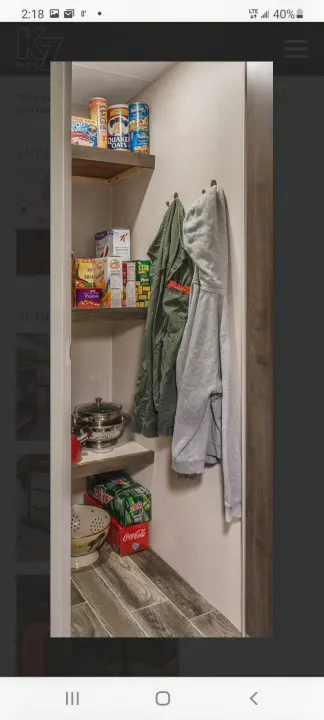 RV rental: Compact pantry for travel storage, with shelves of food, cookware, and hanging jackets for organized living.. Other Sportsmen 2019