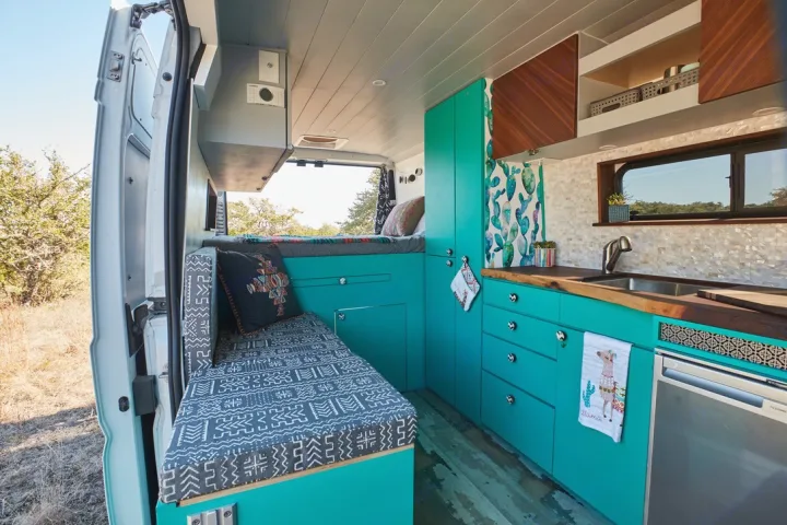 Inside a colorful **rv rental**: bright teal camper van interior featuring a bed, kitchen, and patterned accents. Perfect for travel.. Dodge 2500 Promaster 2019