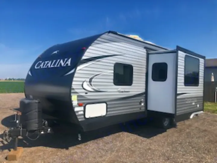 Experience adventure with this stylish gray and black Catalina travel trailer RV rental, featuring an open door and slide-out.. Catalina 221TBS 2018