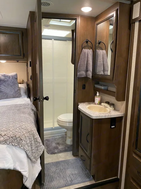 RV rental interior: cozy bedroom and well-equipped bathroom with shower, toilet, and vanity. Comfortable travel living.. Coachmen Prism 2019