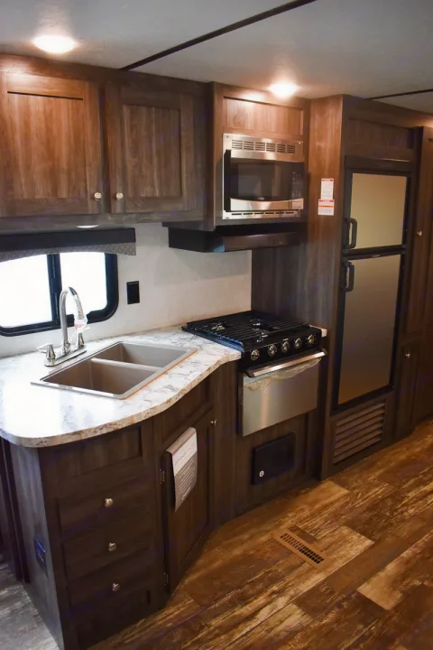RV rental kitchen interior: Modern compact setup featuring a sink, stove, microwave, and fridge for comfortable travel.. Starcraft Autumn Ridge 2020