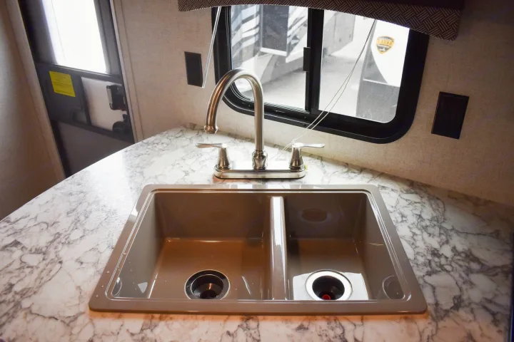 Compact RV rental kitchen sink with modern faucet, double basin, and marble-look countertop. Perfect for travel.. Starcraft Autumn Ridge 2020