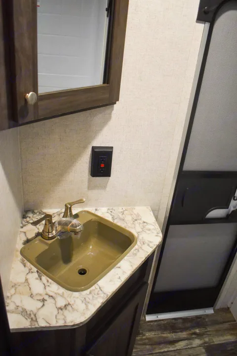 Compact RV rental bathroom vanity featuring a khaki sink, marble counter, mirror, and GFCI outlet. Essential amenities.. Starcraft Autumn Ridge 2020