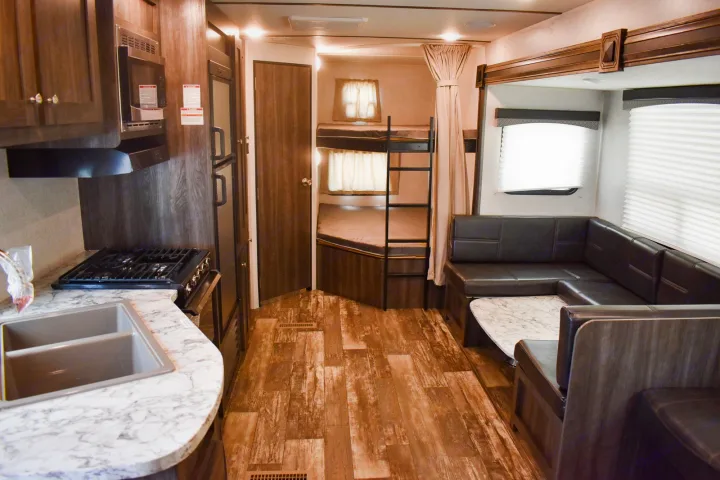 Cozy RV rental interior with kitchen, bunk beds, and U-shaped dinette. Ideal for family trips.. Starcraft Autumn Ridge 2020