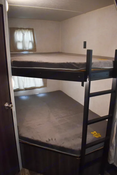 RV rental bunkhouse: two cozy beds with grey mattresses, windows, and ladder. Perfect for family sleeping arrangements.. Starcraft Autumn Ridge 2020