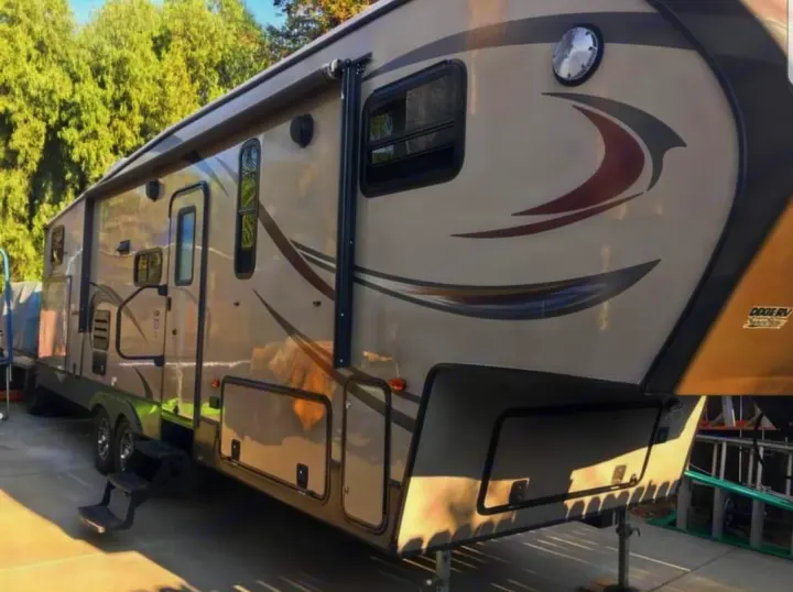 This spacious fifth-wheel RV, ideal for an rv rental, features an awning, multiple windows, and storage compartments.. Forest River Crusader 2015