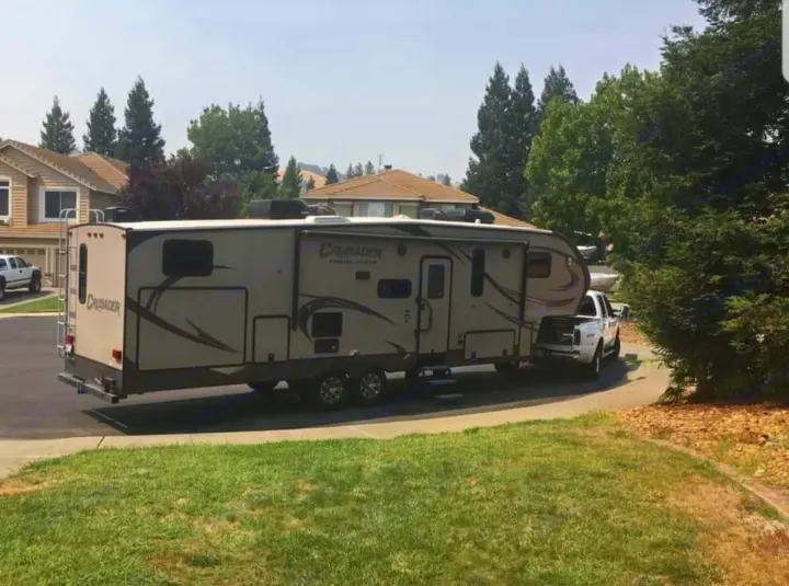 This Crusader fifth-wheel RV, perfect for an RV rental, is hitched to a pickup truck in a residential area.. Forest River Crusader 2015