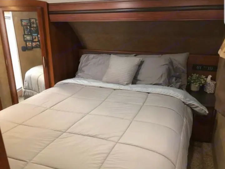 This cozy RV rental bedroom features a comfortable bed with gray bedding, a mirrored closet, and a nightstand.. Forest River Crusader 2015