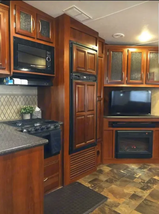 This spacious RV rental interior features a kitchen with stove, microwave, fridge, plus a TV and fireplace.. Forest River Crusader 2015