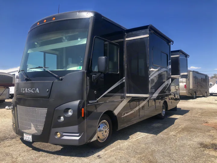 This dark grey Itasca motorhome, an ideal RV rental, is parked in a sunny lot with other RVs.. Itasca Sunstar 2015