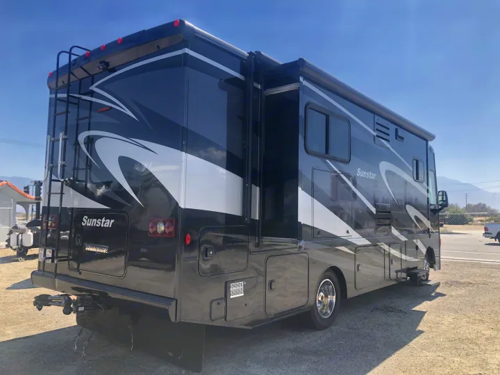 Black Winnebago Sunstar RV rental parked outdoors, showcasing its spacious exterior with an extended slide-out.. Itasca Sunstar 2015