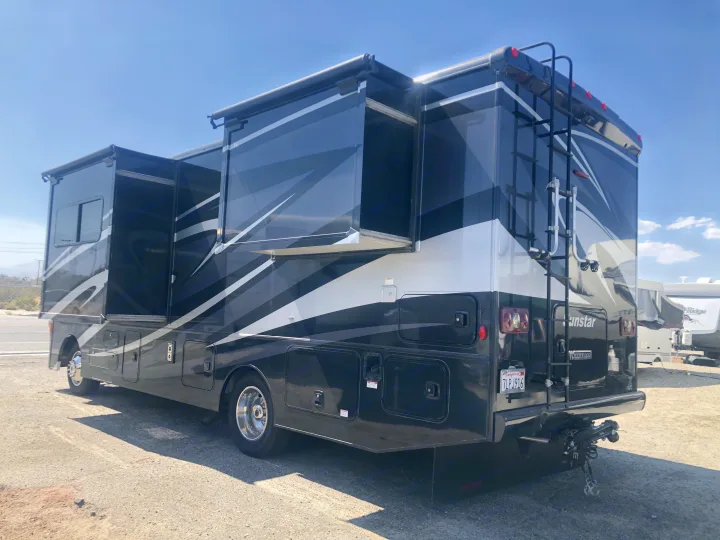Spacious black and white Winnebago Sunstar rv rental with slide-outs extended, parked outdoors.. Itasca Sunstar 2015