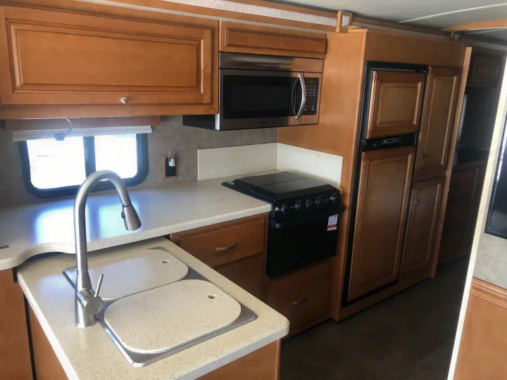 RV rental: Spacious kitchen with light wood cabinets, microwave, sink, stovetop, and fridge for comfortable travel.. Itasca Sunstar 2015