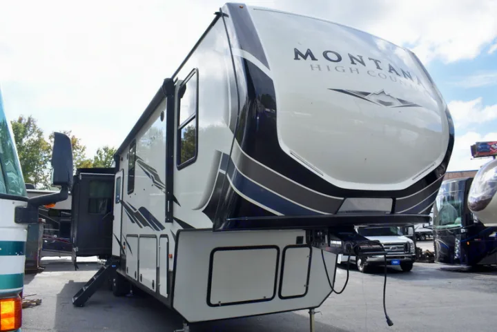A white & black Montana High Country fifth-wheel RV for rental, with extended awning, slide-out, and deployed steps.. Other Montana High Country 2021