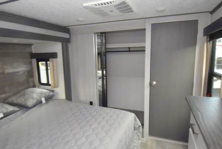 Modern RV rental bedroom with bed, sliding closet, and AC unit for comfortable travel.. Other Montana High Country 2021