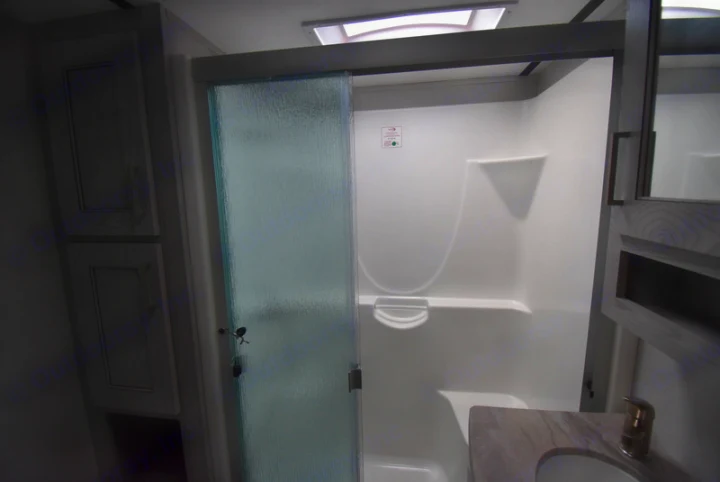 Modern RV rental bathroom: large shower with frosted sliding door, built-in seat, vanity & storage.. Other Montana High Country 2021