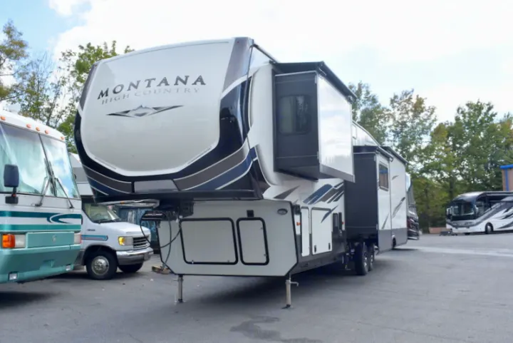Large white and black Montana High Country fifth-wheel RV with extended slide-outs, parked in an RV rental or sales lot.. Other Montana High Country 2021